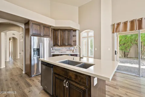 a kitchen with stainless steel appliances granite countertop a sink a refrigerator and a wooden floors