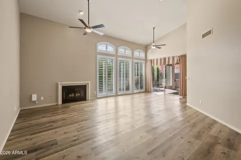 a view of a livingroom with wooden floor a ceiling fan and windows