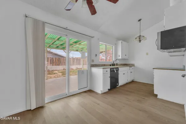a kitchen with a sink wooden floor and a view of living room
