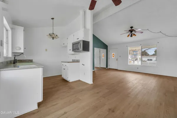 a view of a kitchen with a sink dishwasher a kitchen island with wooden floor and cabinets
