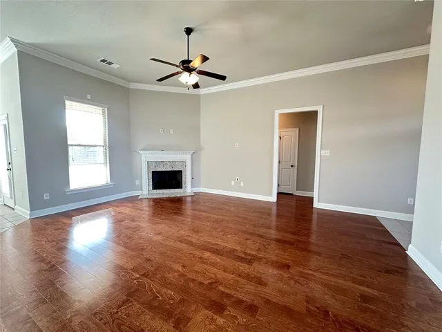 an empty room with wooden floor fireplace and windows