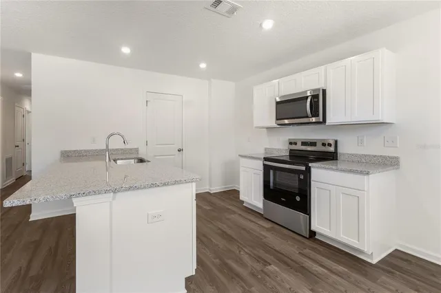 a kitchen with granite countertop a sink and steel appliances