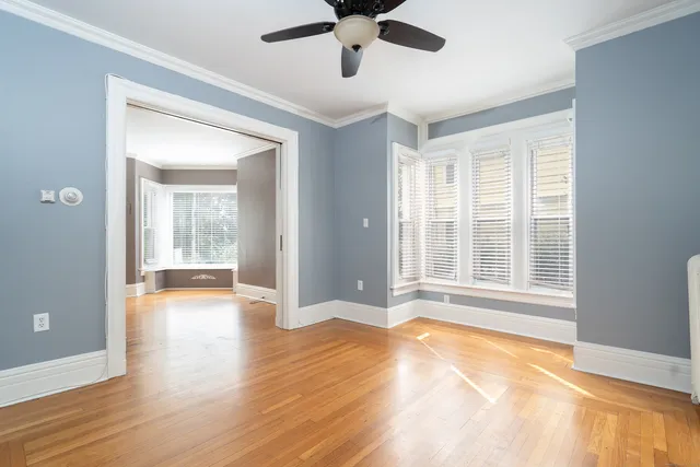 a view of an empty room with window and wooden floor