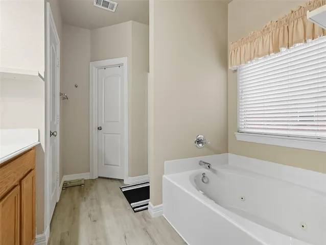 a bathroom with a tub a sink and a window