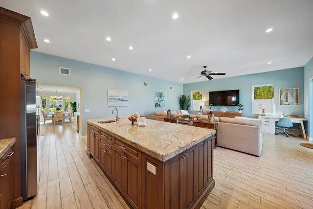 a living room with stainless steel appliances granite countertop sink wooden floor table and chairs