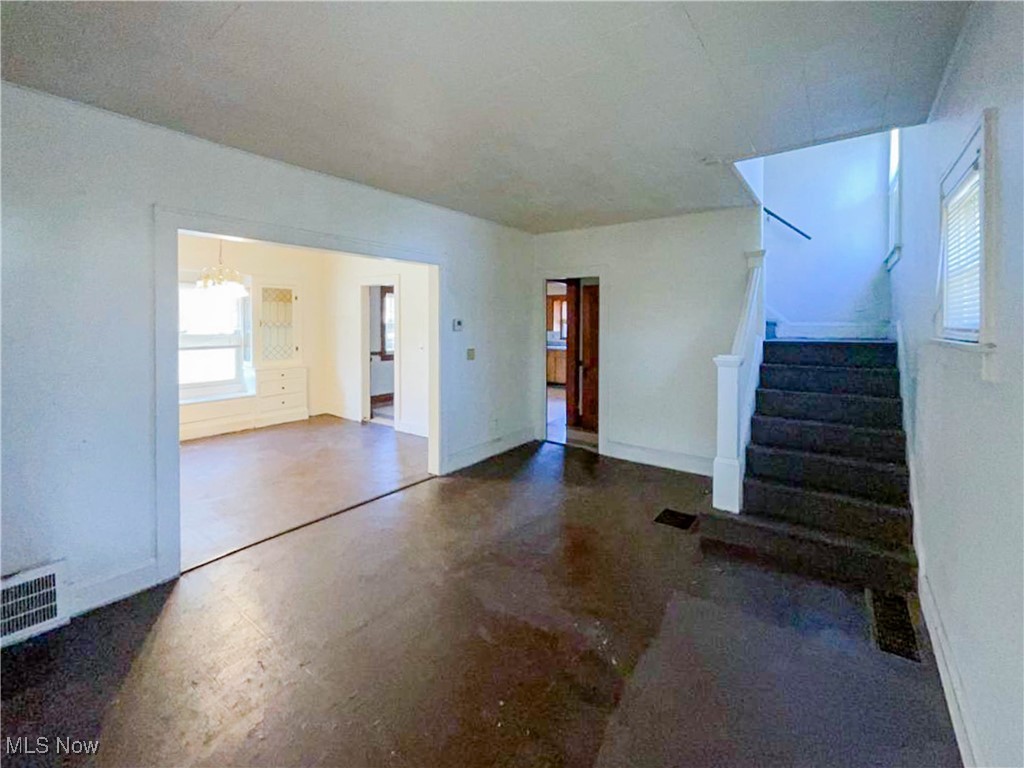 14703 Granger Road Maple Heights, OH 44137 - Photo 7 of 35 Unfurnished living room with baseboards, an inviting chandelier, finished concrete flooring, stairs, and visible vents