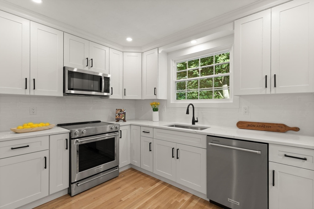 77 Morton Street Canton, MA 02021 - Photo 5 of 28 a kitchen with stainless steel appliances granite countertop white cabinets a sink a stove a window and island with wooden floor