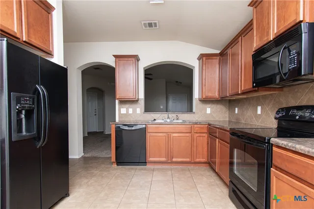a kitchen with stainless steel appliances granite countertop a sink and a refrigerator