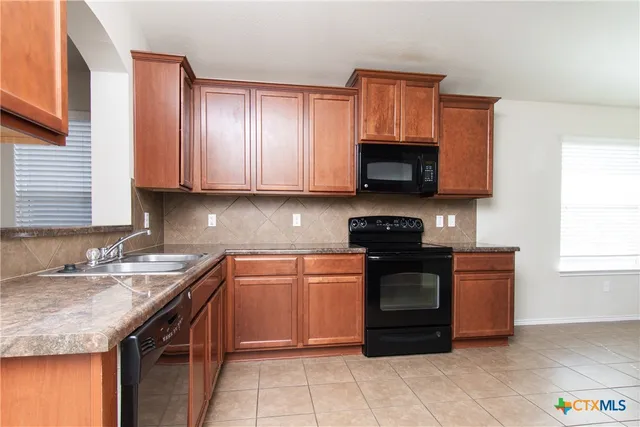 a kitchen with stainless steel appliances granite countertop wooden cabinets and a stove top oven