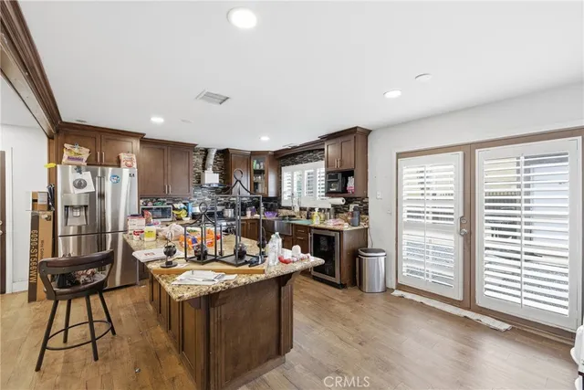 a view of a kitchen with kitchen island a stove a refrigerator a dining table and chairs with wooden floor