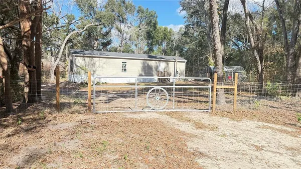 a view of a backyard with wooden fence and large trees