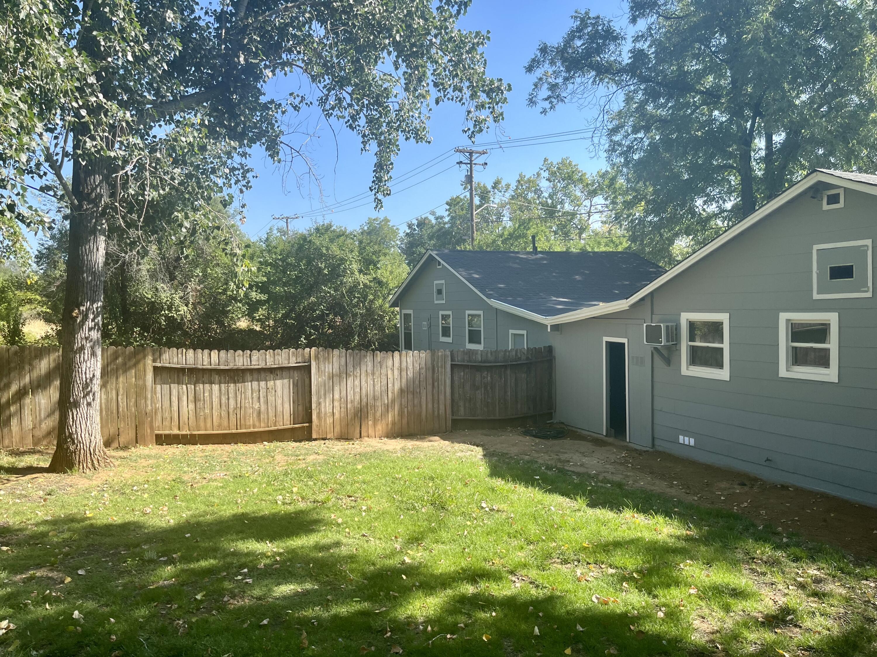 4980-4990 Cedars Road Redding, CA 96001 - Photo 46 of 67 a backyard of a house with large trees and wooden fence