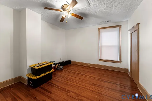 a room with wooden floor and ceiling fan