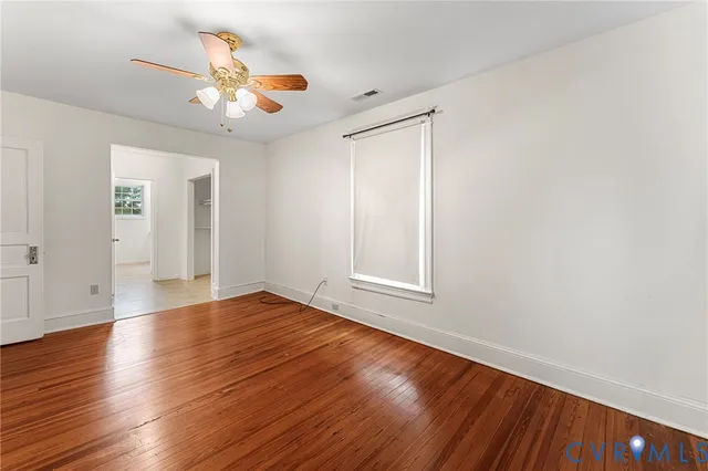 a view of an empty room with window and wooden floor