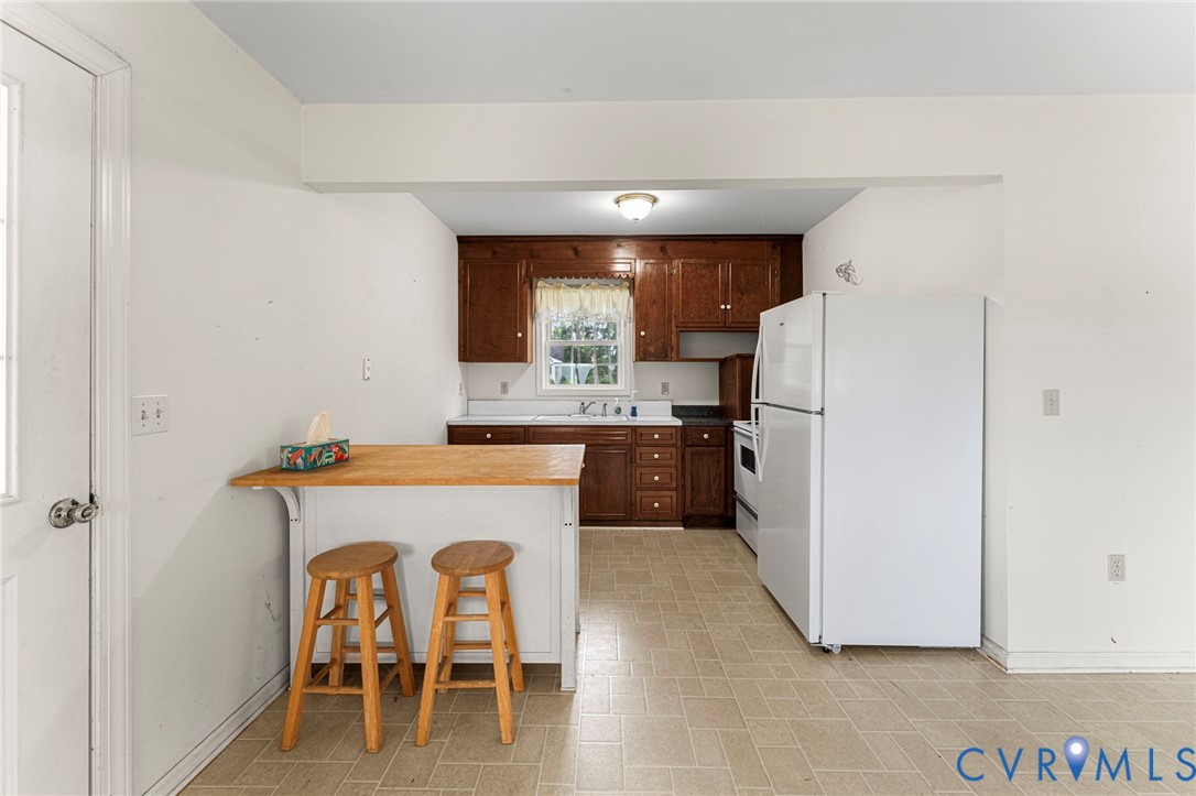 4516 Oldhams Road Hague, VA 22469 - Photo 8 of 23 a kitchen with refrigerator cabinets dining table and chairs