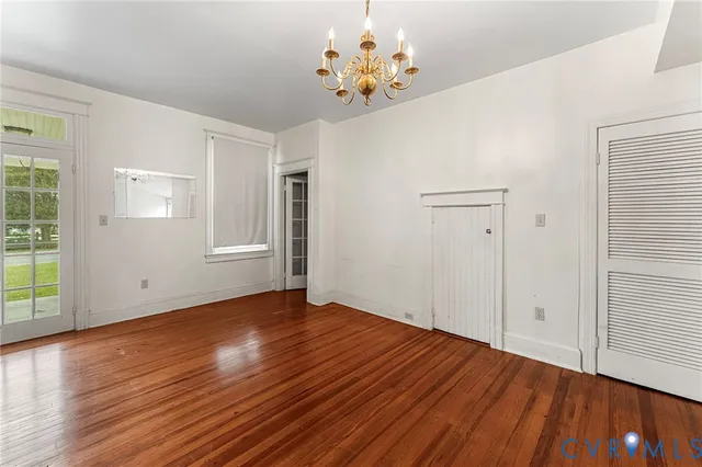 a view of an empty room with wooden floor and a kitchen