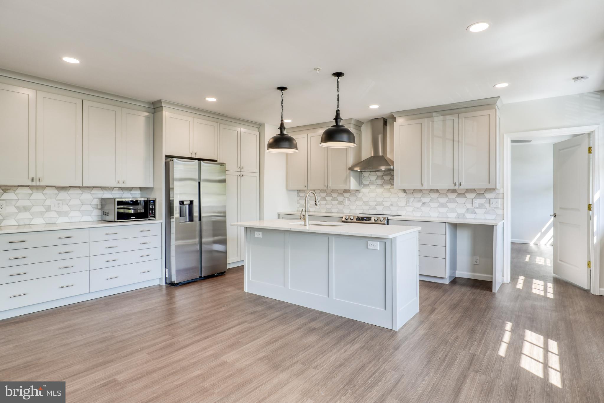 a large kitchen with a center island stainless steel appliances and cabinets
