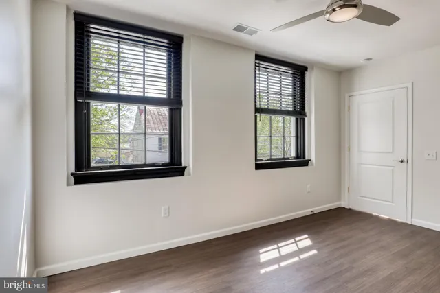 a view of an empty room with wooden floor and windows