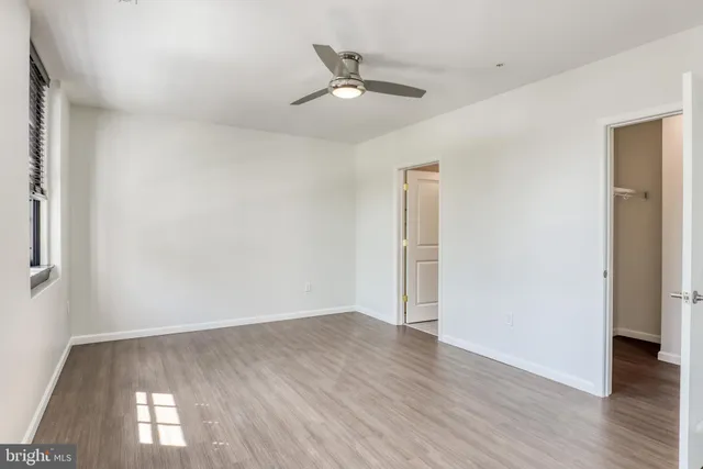 an empty room with wooden floor and a ceiling fan