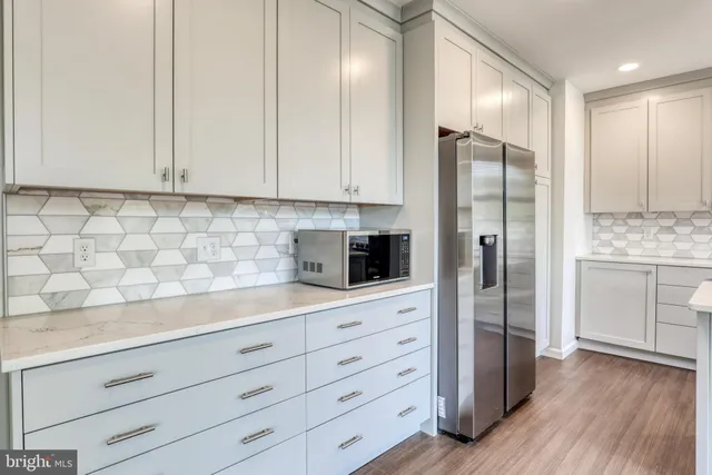 a kitchen with a refrigerator and white cabinets