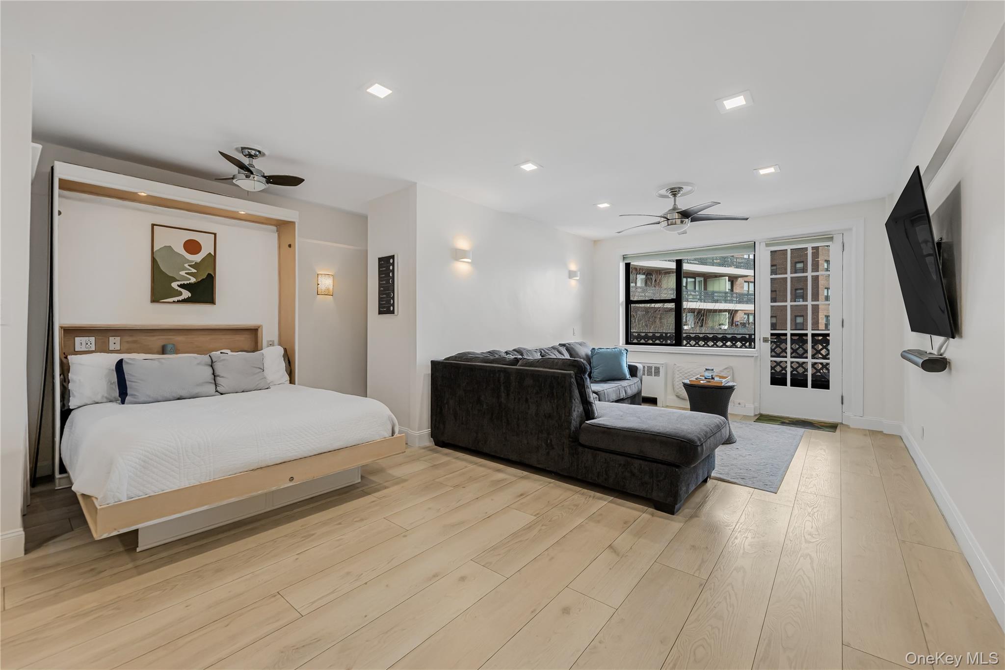 a spacious bedroom with a bed a couch and a flat screen tv