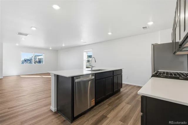 a kitchen with stainless steel appliances granite countertop a sink stove and wooden floor