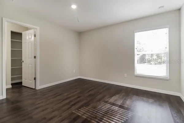 a view of an empty room with wooden floor and a window