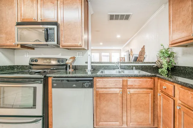 a kitchen with stainless steel appliances granite countertop a sink a stove and a microwave