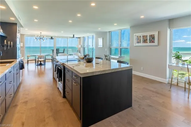 a open kitchen with kitchen island a sink a stove and a refrigerator with wooden floor