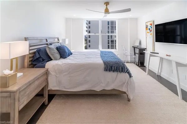 a spacious bedroom with a bed and a flat screen tv