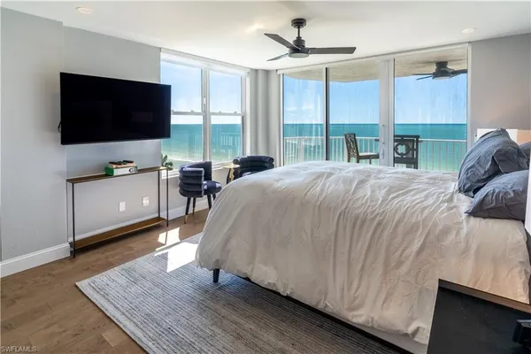 a living room with a bed furniture flat screen tv and a large window