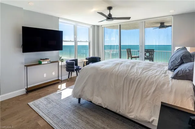 a living room with a bed furniture flat screen tv and a large window