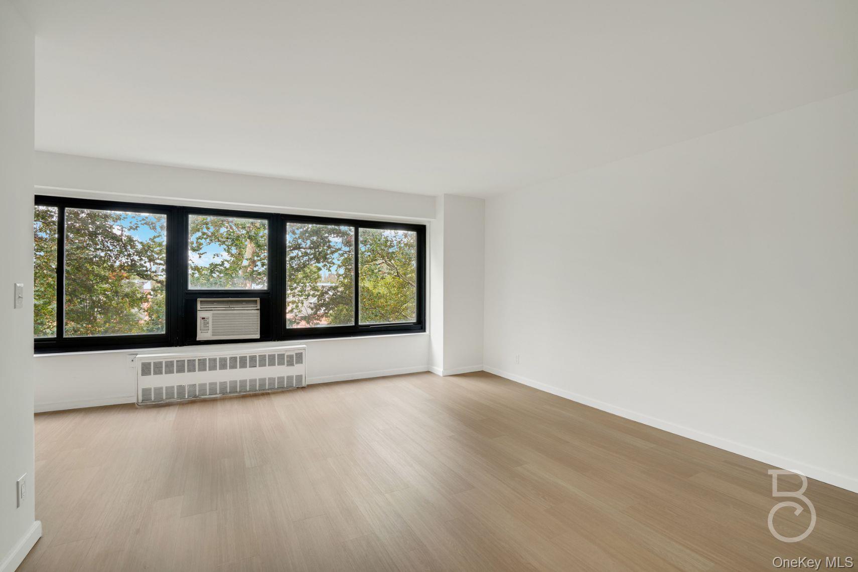 33-43 14th Street, Unit 4B Queens, NY 11106 - Photo 11 of 19 an empty room with wooden floor and windows