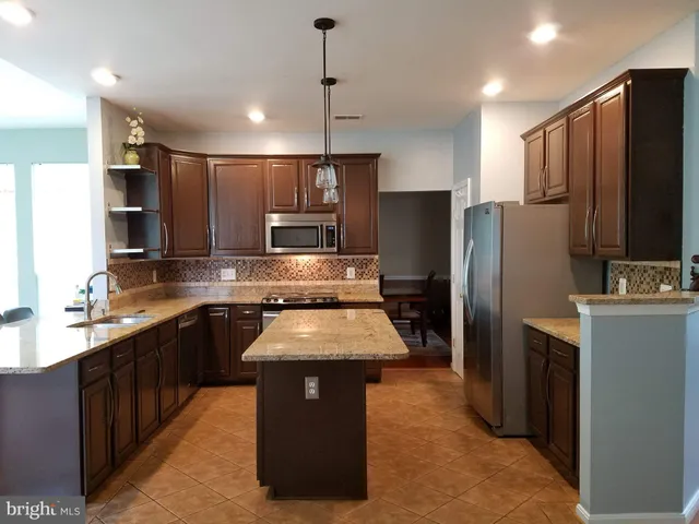 a kitchen with kitchen island a counter top space stainless steel appliances and cabinets