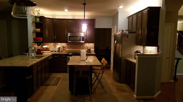 a kitchen with kitchen island a counter top space cabinets and stainless steel appliances