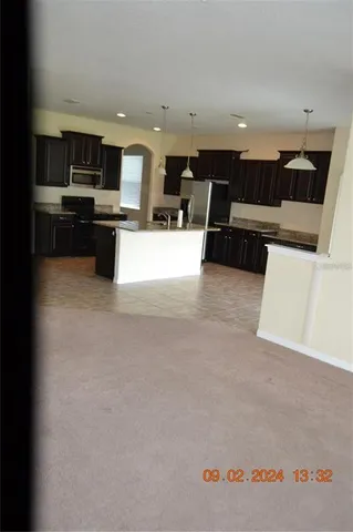 a living room with stainless steel appliances furniture and a view of kitchen
