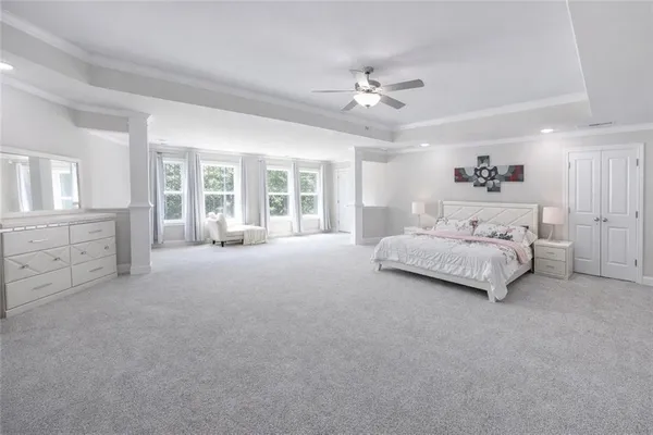 a spacious bedroom with a large bed and a chandelier