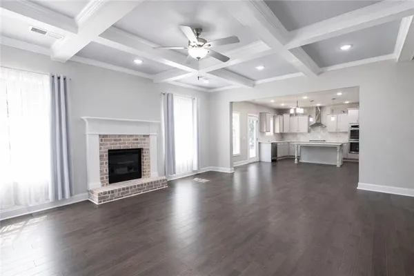 an empty room with wooden floor fireplace and windows