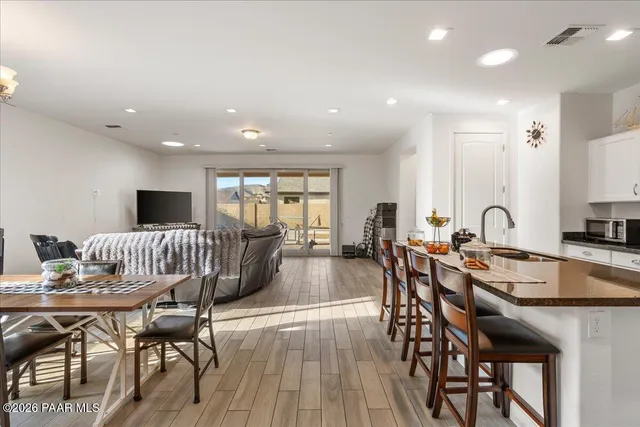 a kitchen with stainless steel appliances granite countertop a stove a sink dishwasher a dining table and chairs with wooden floor