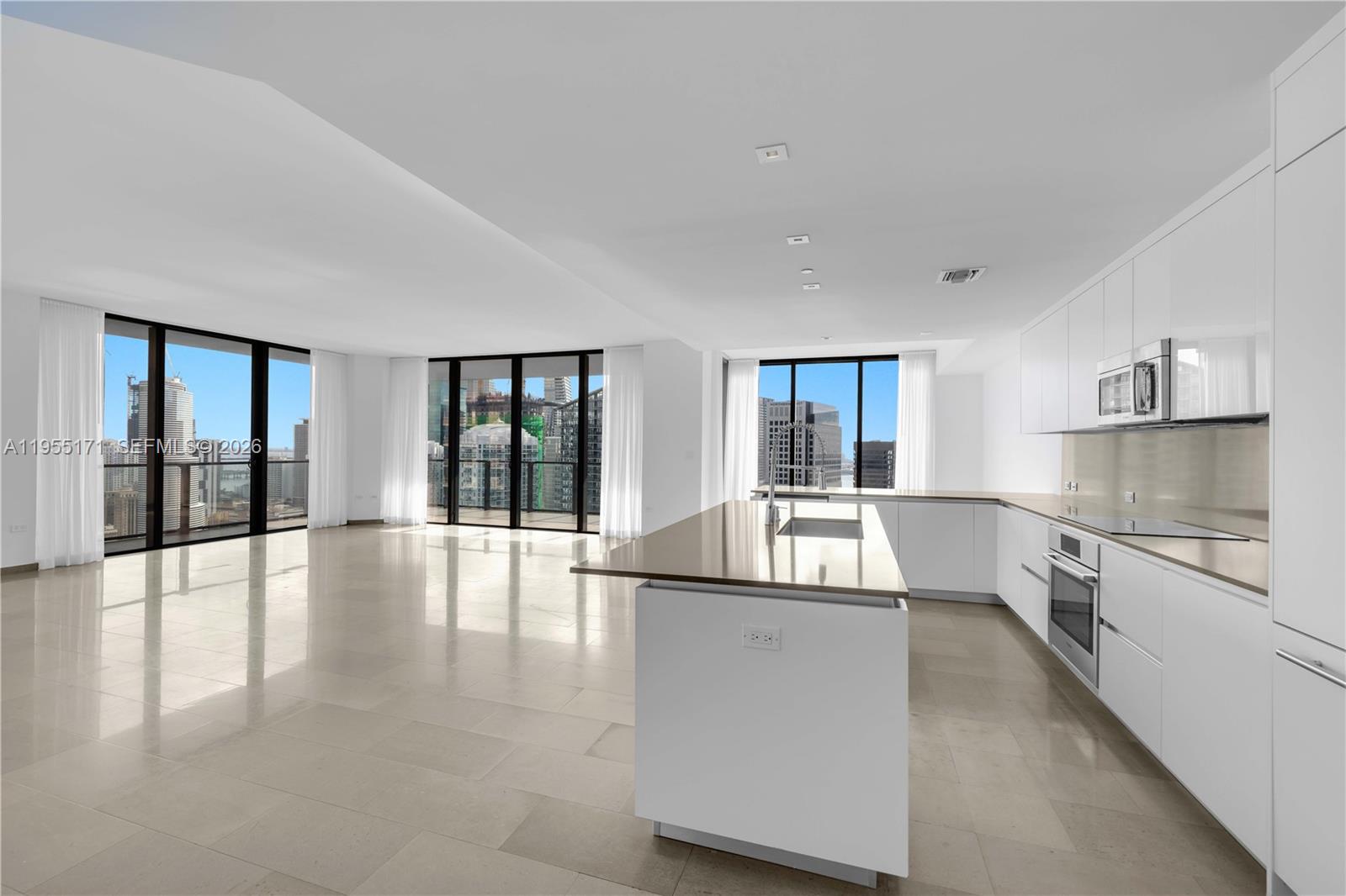 a large white kitchen with granite countertop a large window