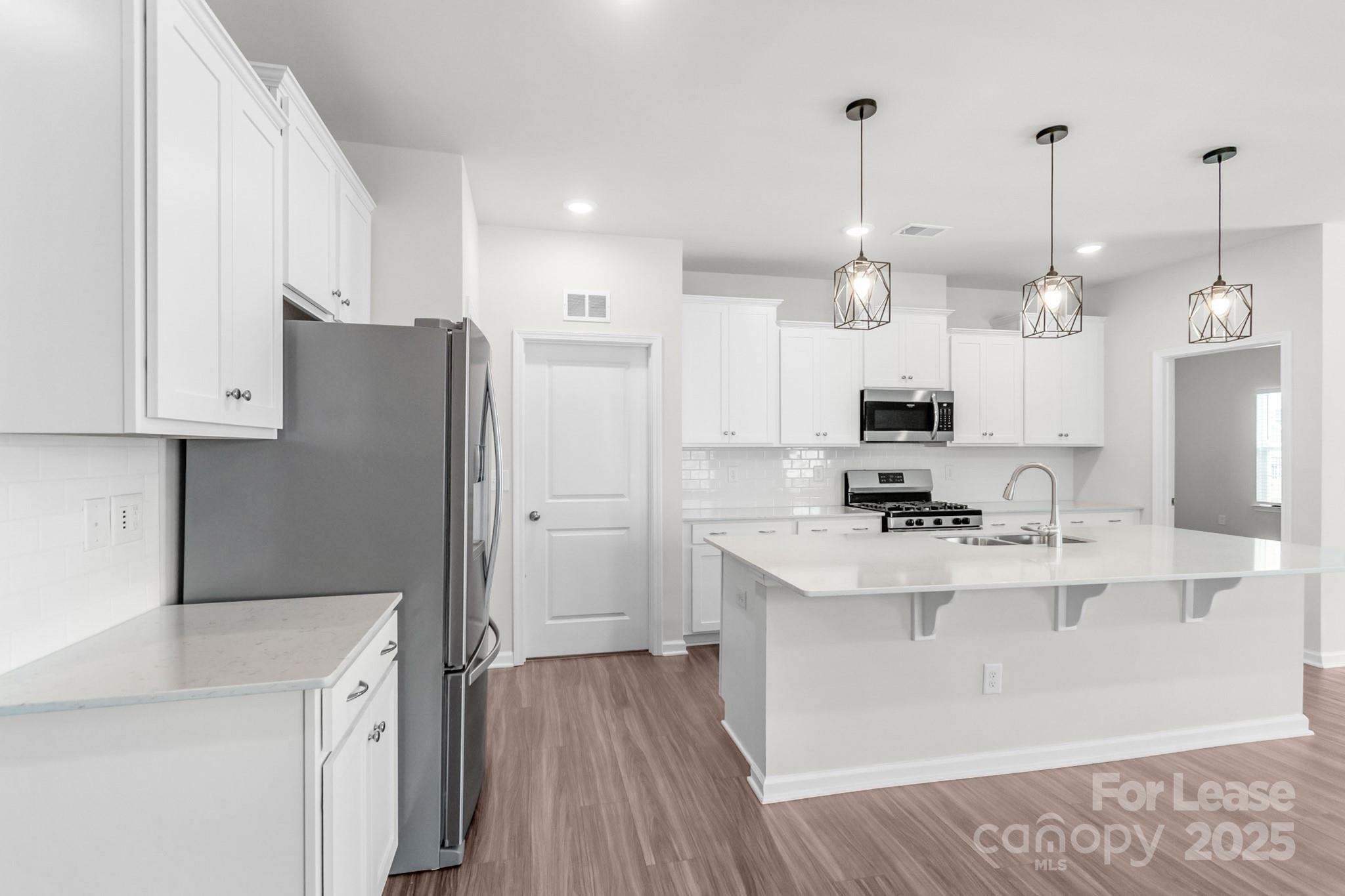 15520 Capps Road Charlotte, NC 28278 - Photo 13 of 48 a kitchen with stainless steel appliances kitchen island granite countertop a refrigerator a sink dishwasher a stove and white cabinets with wooden floor