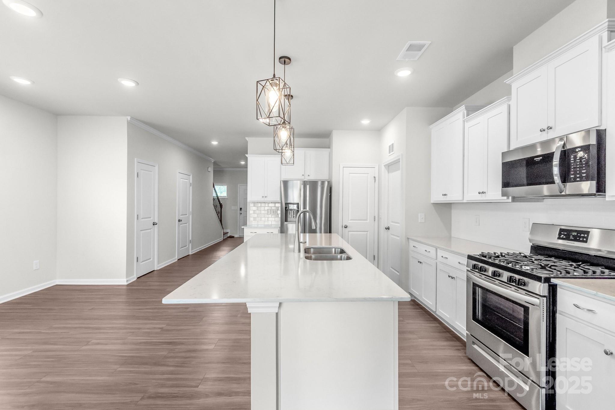 15520 Capps Road Charlotte, NC 28278 - Photo 14 of 48 a large kitchen with kitchen island a stove a sink a refrigerator and a wooden floor