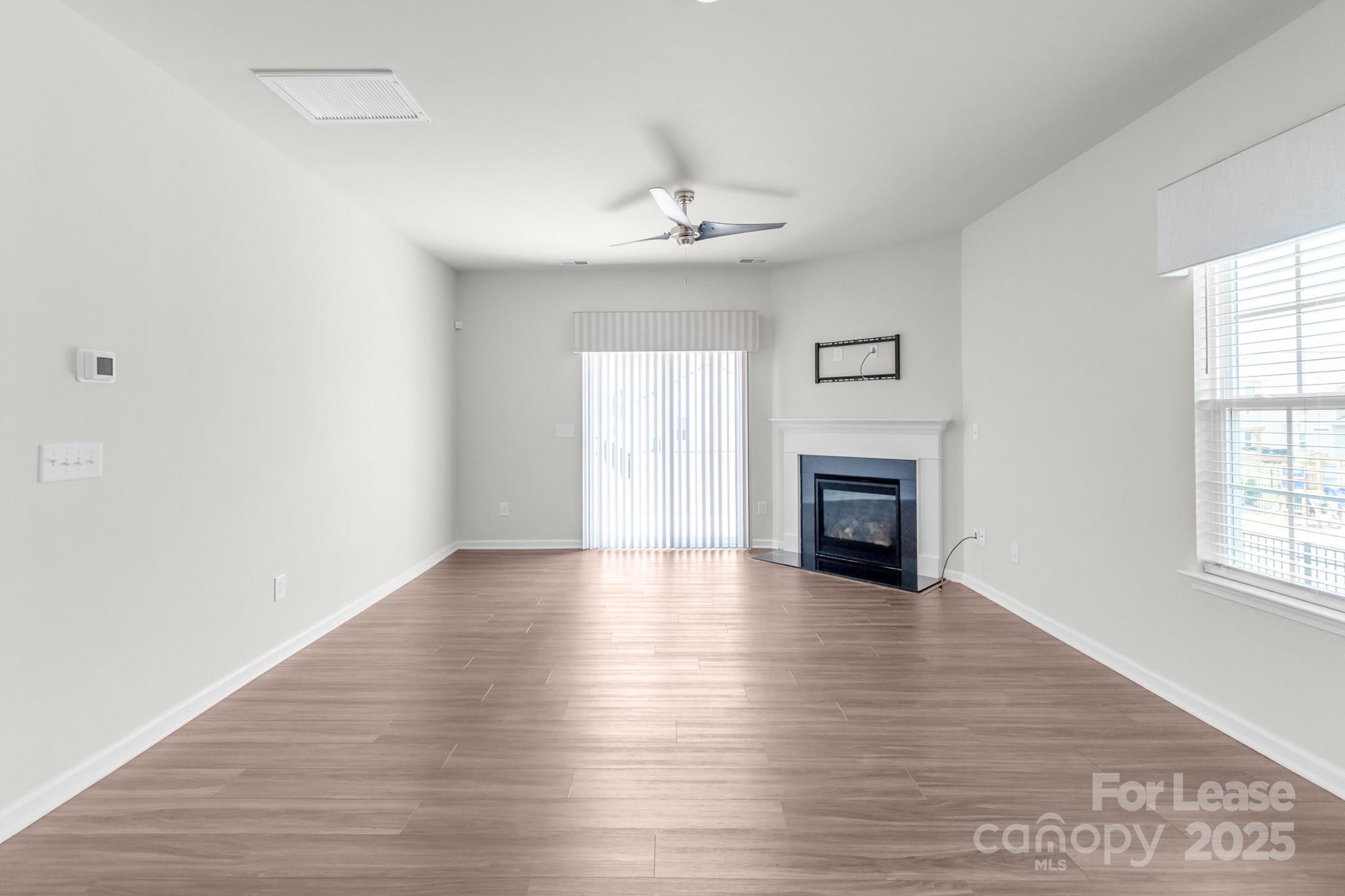 15520 Capps Road Charlotte, NC 28278 - Photo 8 of 48 an empty room with wooden floor fireplace and windows