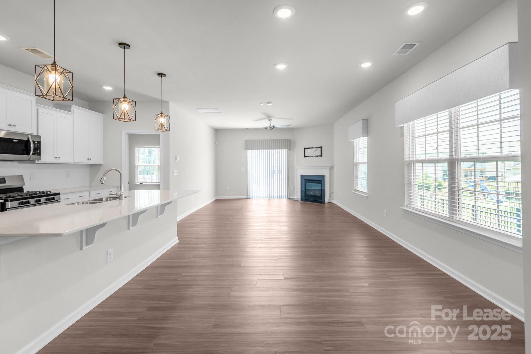 15520 Capps Road Charlotte, NC 28278 - Photo 10 of 48 a large kitchen with stainless steel appliances a large counter top a stove a sink dishwasher a microwave oven and a large window with wooden floor