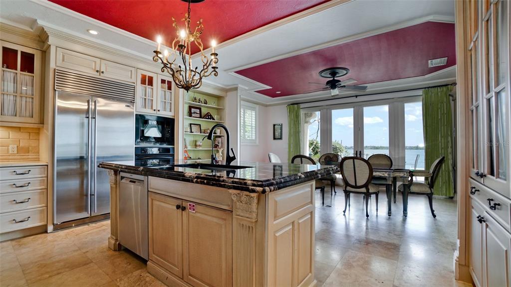 8213 Midnight Pass Road Sarasota, FL 34242 - Photo 13 of 52 a kitchen with stainless steel appliances granite countertop a stove top oven a refrigerator a dining table and chairs with wooden floor