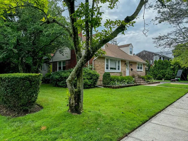 a front view of a house with a yard and green space