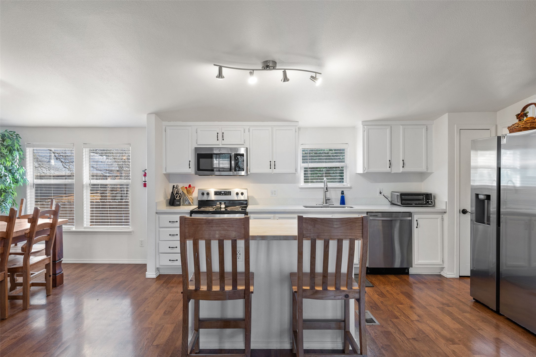 5519 Hiline Road Austin, TX 78734 - Photo 6 of 40 a kitchen with stainless steel appliances granite countertop a stove top oven a sink dishwasher a dining table and chairs with wooden floor