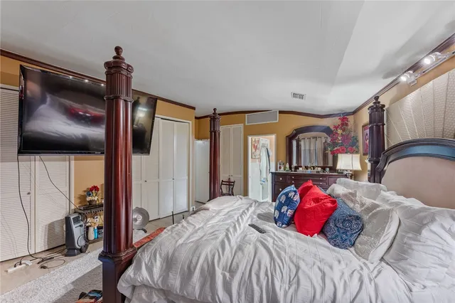 a bedroom with a large bed and a flat tv screen on dresser