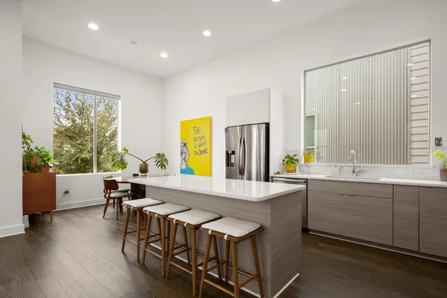 a kitchen with stainless steel appliances granite countertop a table chairs and a refrigerator