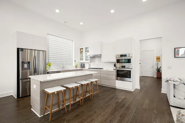 a kitchen with stainless steel appliances granite countertop a table chairs stove and white cabinets